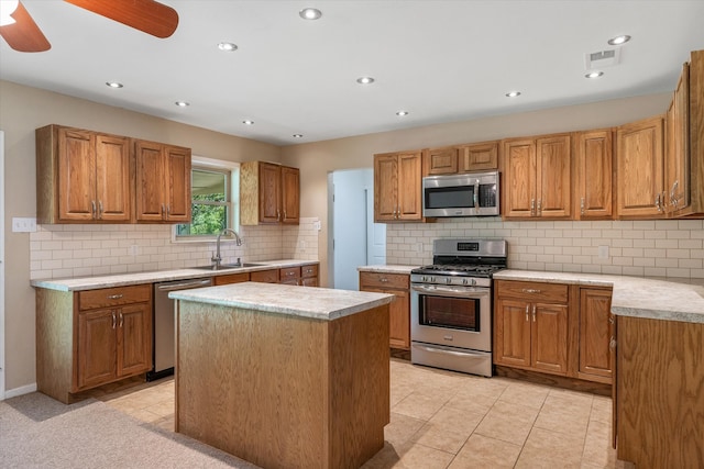 kitchen with ceiling fan, stainless steel appliances, decorative backsplash, sink, and a center island