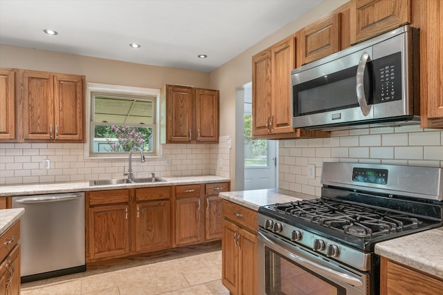 kitchen with sink, light tile patterned flooring, decorative backsplash, and stainless steel appliances