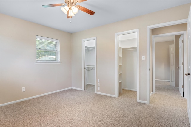 unfurnished bedroom with a walk in closet, ceiling fan, and light colored carpet