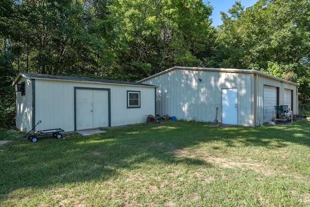 rear view of property featuring a garage, a lawn, and an outdoor structure