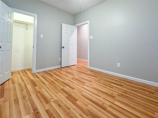 unfurnished bedroom featuring a closet, baseboards, and light wood finished floors