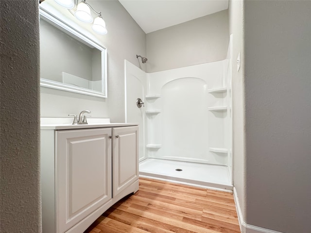 bathroom with a shower, wood-type flooring, and vanity