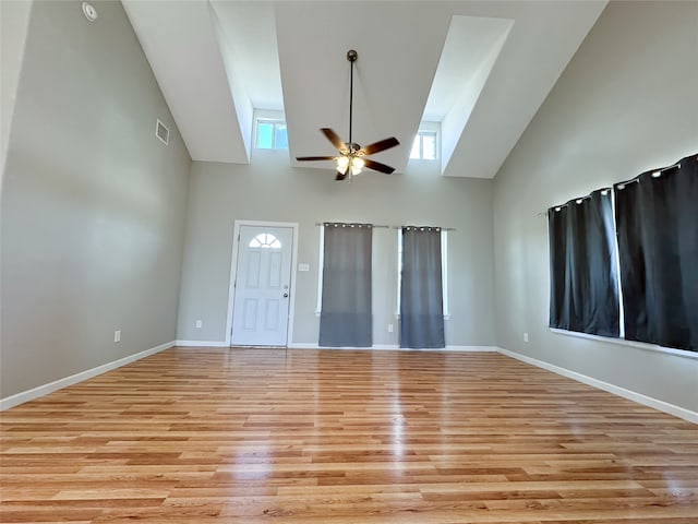 empty room featuring ceiling fan, light hardwood / wood-style floors, and a high ceiling