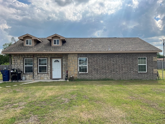 view of front facade with roof with shingles and a front yard