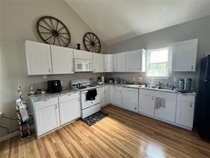 kitchen with light countertops, white appliances, white cabinetry, and lofted ceiling