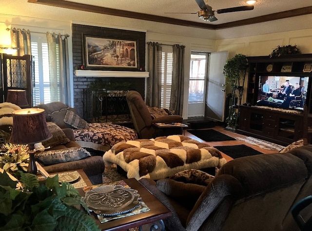 living room featuring a textured ceiling, a fireplace, ceiling fan, and crown molding