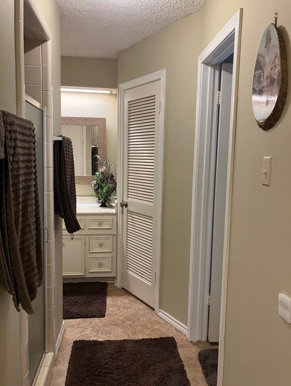 bathroom with a textured ceiling, tile patterned floors, vanity, and an enclosed shower