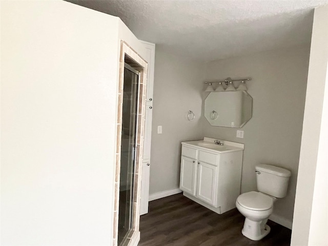 bathroom featuring a shower with door, vanity, wood-type flooring, a textured ceiling, and toilet