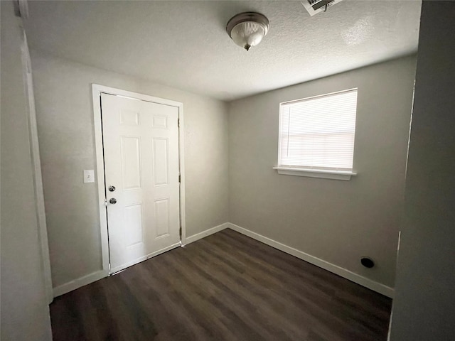 spare room with dark hardwood / wood-style floors and a textured ceiling