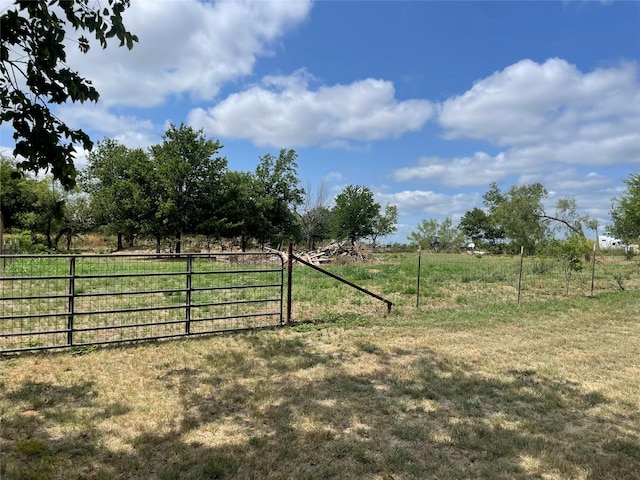 view of gate with a lawn and a rural view