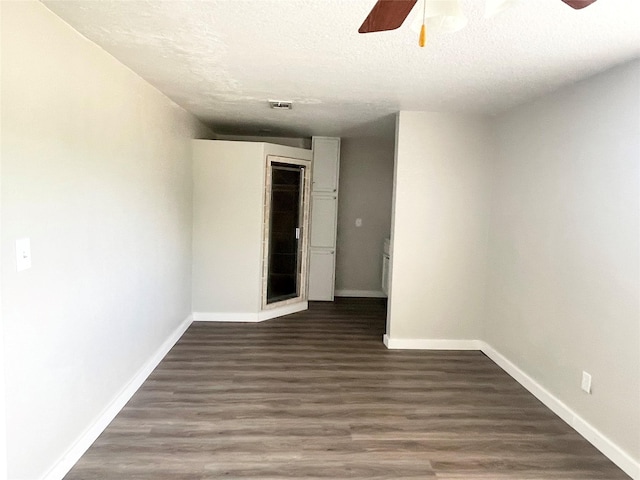 spare room featuring ceiling fan, dark hardwood / wood-style flooring, and a textured ceiling