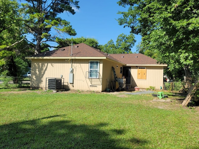 rear view of house featuring central AC and a yard