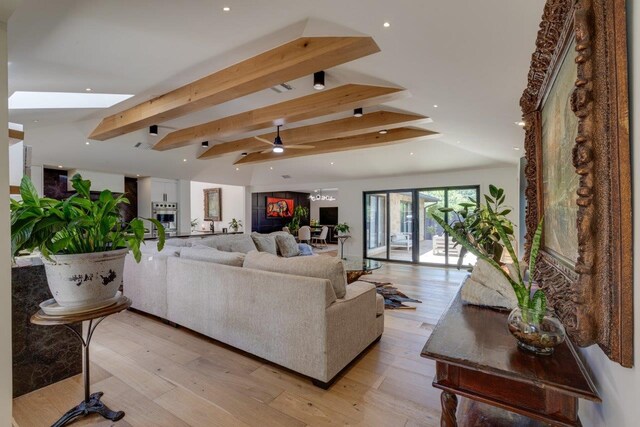 living room featuring vaulted ceiling with skylight and light hardwood / wood-style flooring