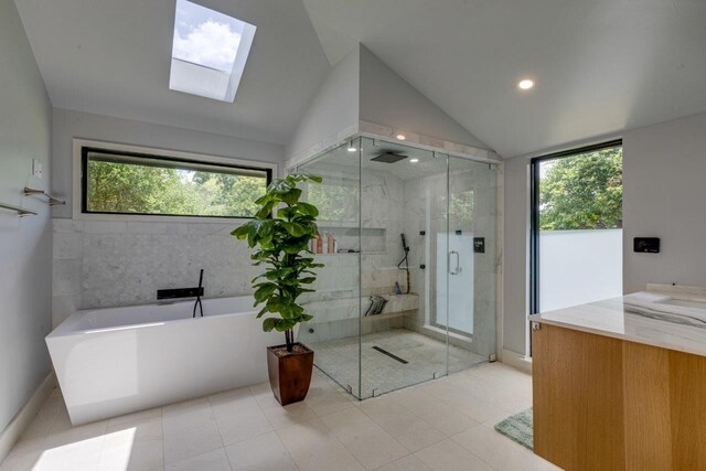 bathroom featuring vanity, tile patterned floors, independent shower and bath, and vaulted ceiling with skylight