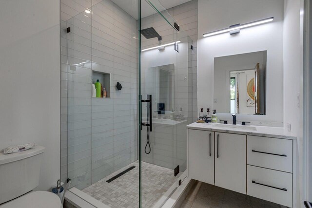 bathroom with tile patterned floors, vanity, toilet, and an enclosed shower