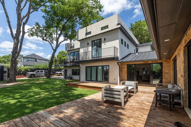 back of house with a balcony, an outdoor hangout area, a deck, and a lawn