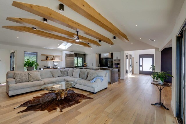 living room with lofted ceiling with skylight and light hardwood / wood-style flooring