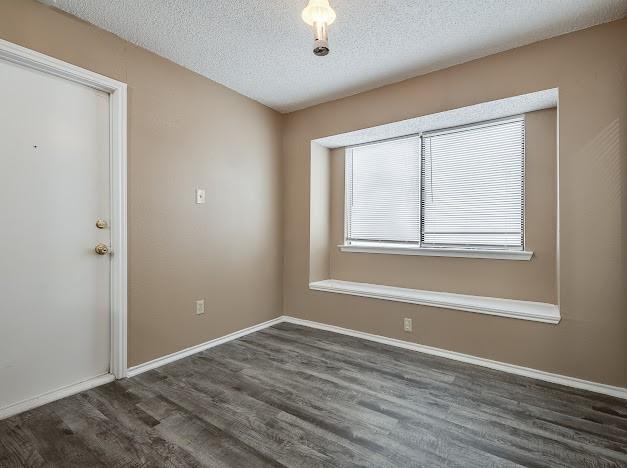 unfurnished room with a textured ceiling and dark hardwood / wood-style floors