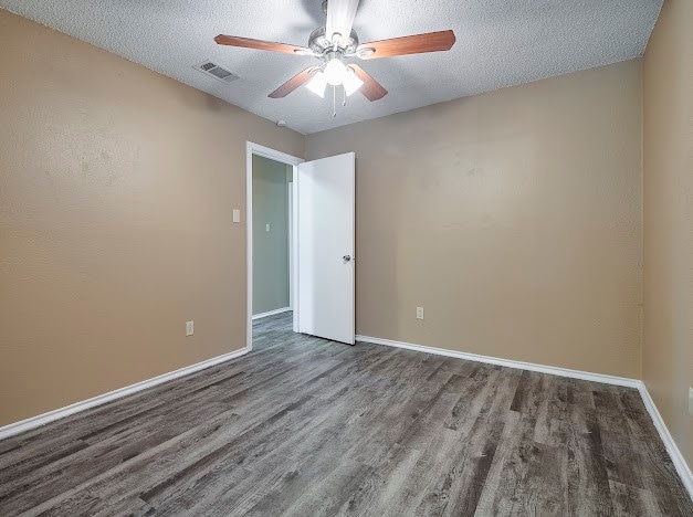 unfurnished room with a textured ceiling, ceiling fan, and wood-type flooring