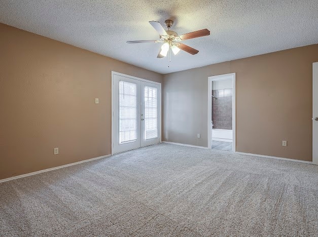 spare room featuring carpet, ceiling fan, french doors, and a textured ceiling