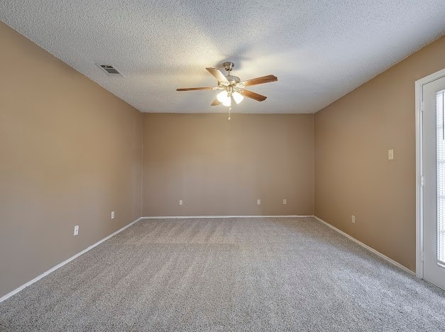 carpeted spare room featuring a textured ceiling, ceiling fan, and a healthy amount of sunlight