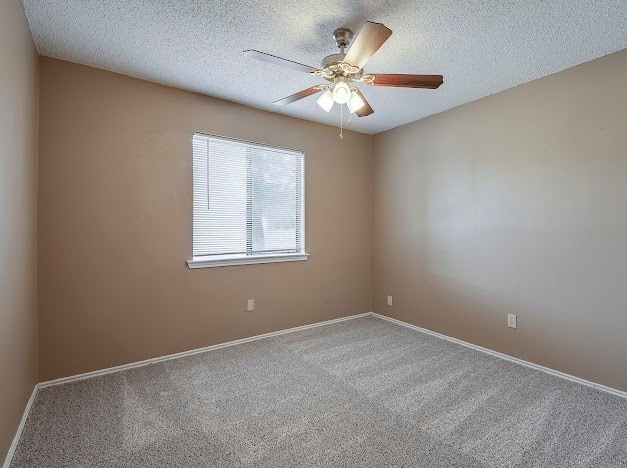 unfurnished room with carpet, ceiling fan, and a textured ceiling