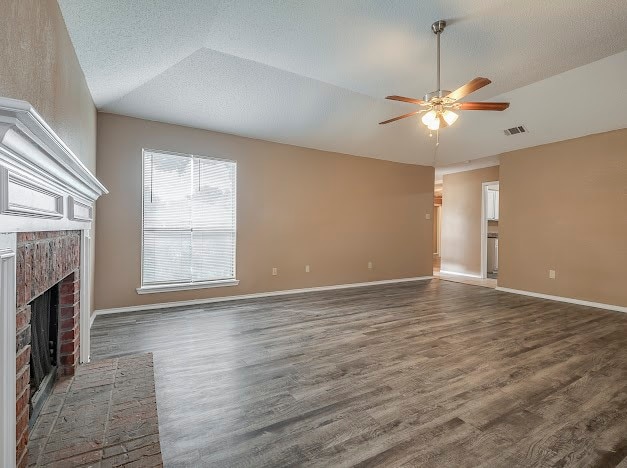 unfurnished living room featuring lofted ceiling, a textured ceiling, ceiling fan, hardwood / wood-style floors, and a fireplace