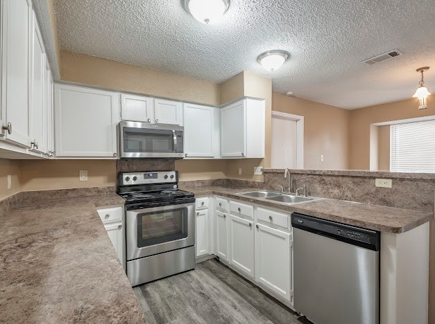 kitchen featuring sink, light wood-type flooring, stainless steel appliances, and white cabinets