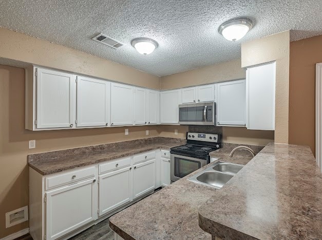 kitchen featuring white cabinets, stainless steel appliances, sink, and a textured ceiling