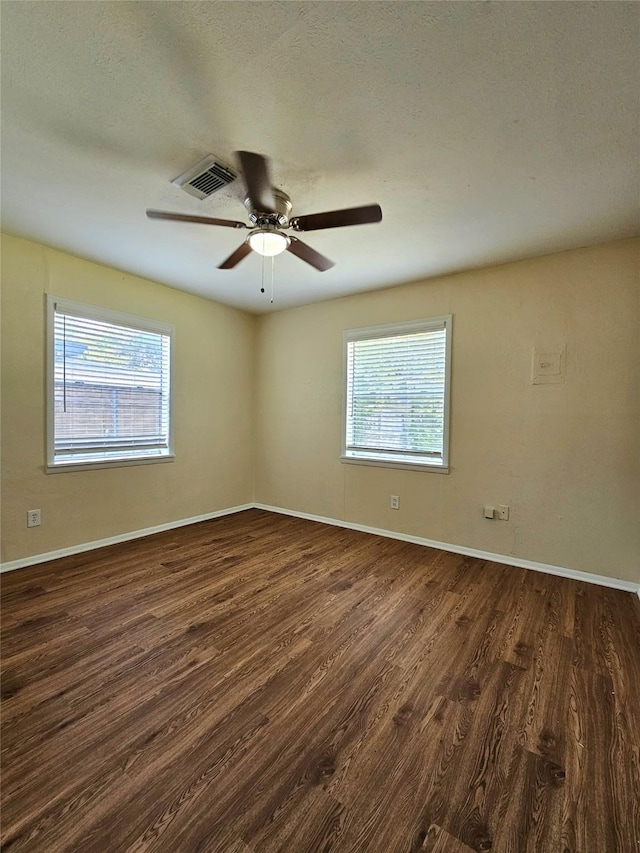 spare room with a textured ceiling, dark wood-type flooring, and ceiling fan