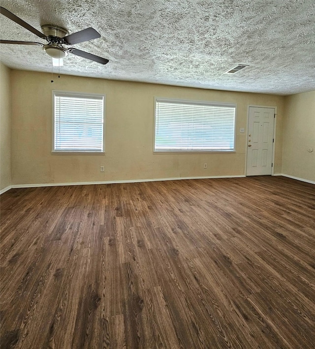 spare room featuring dark wood-type flooring, ceiling fan, plenty of natural light, and a textured ceiling