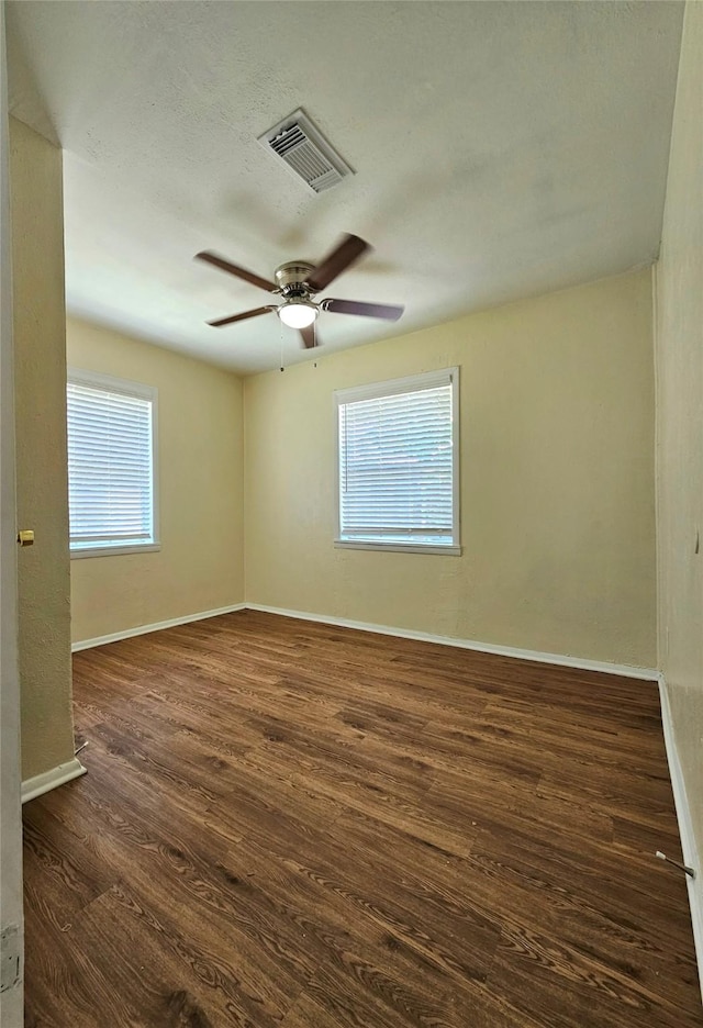 empty room with ceiling fan and dark hardwood / wood-style flooring