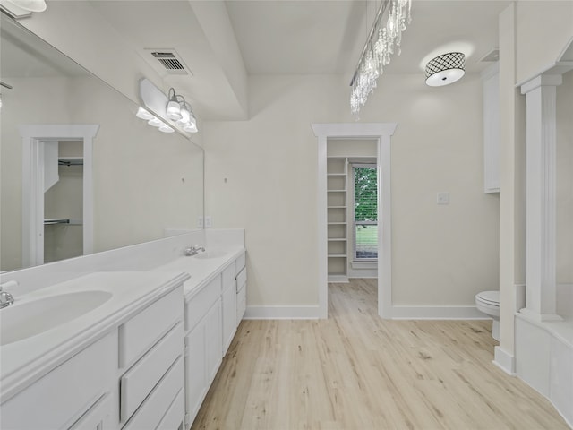 bathroom featuring dual vanity, toilet, and hardwood / wood-style flooring