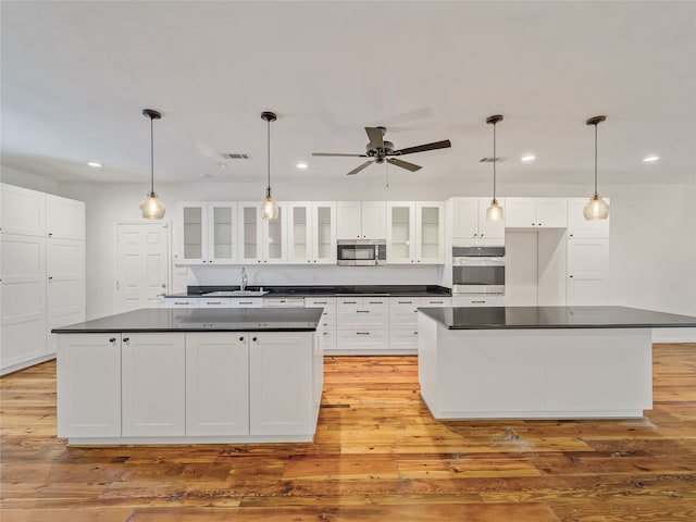 kitchen featuring a kitchen island, appliances with stainless steel finishes, white cabinets, and light hardwood / wood-style floors