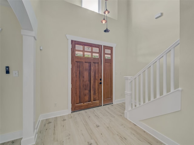 foyer entrance with light wood-type flooring and a towering ceiling