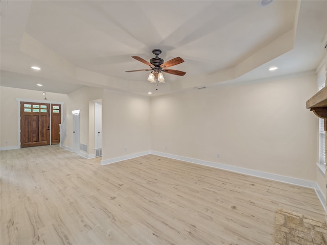 unfurnished living room with a raised ceiling, light wood-type flooring, and ceiling fan