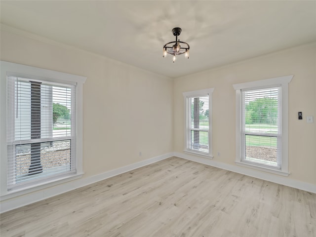 spare room featuring light hardwood / wood-style floors and an inviting chandelier