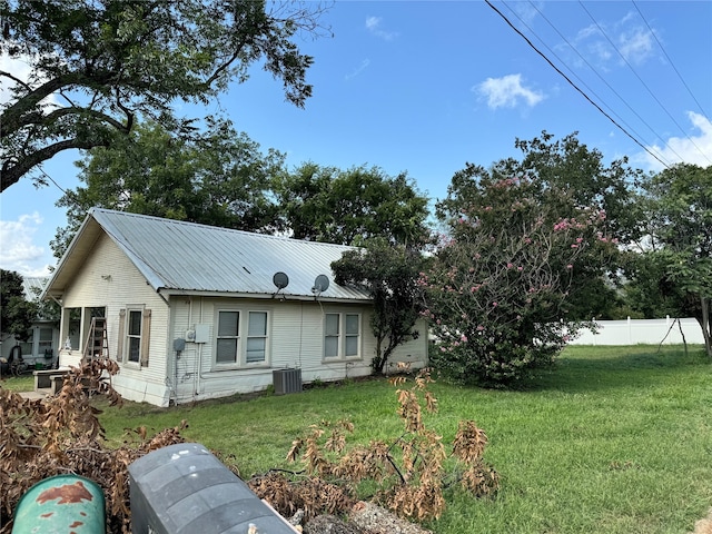 exterior space featuring central air condition unit and a front yard