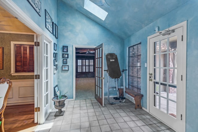 interior space with french doors, tile patterned floors, and vaulted ceiling with skylight