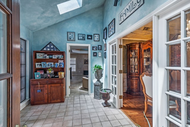 hallway featuring vaulted ceiling with skylight and light tile patterned floors