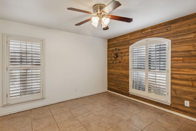 spare room featuring log walls, ceiling fan, and wood walls