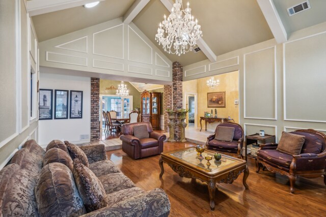 living room with brick wall, a notable chandelier, beam ceiling, and hardwood / wood-style flooring