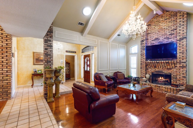 living room featuring a notable chandelier, beam ceiling, a brick fireplace, and light wood-type flooring