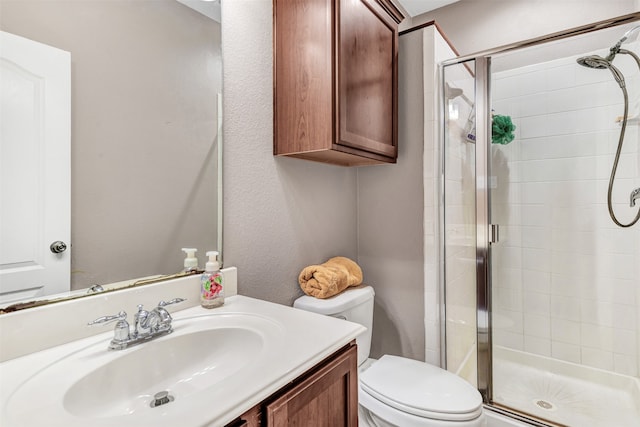 bathroom with a shower with door, vanity, and toilet