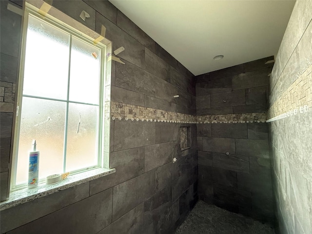 bathroom with a tile shower and a healthy amount of sunlight