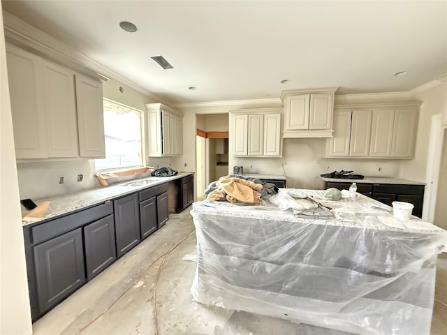 kitchen featuring a kitchen island, crown molding, cream cabinets, and light stone countertops