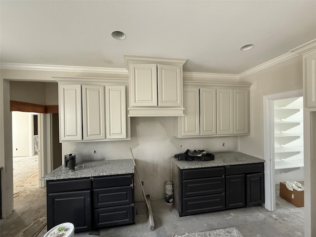 kitchen with light stone counters, crown molding, and cream cabinets