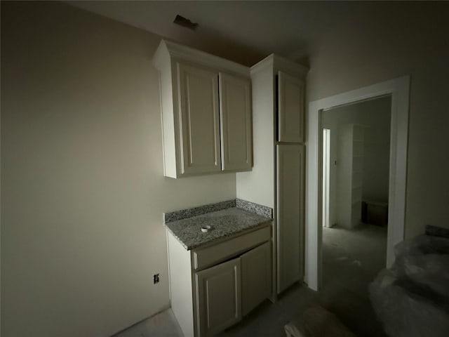 kitchen with white cabinetry and light stone counters