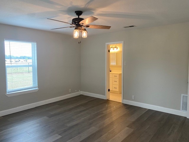 unfurnished bedroom featuring dark wood-type flooring, ceiling fan, and connected bathroom