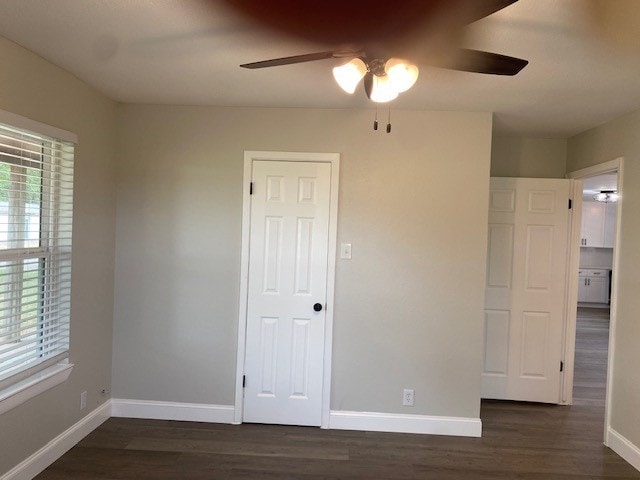 unfurnished bedroom featuring dark wood-style floors, baseboards, and a ceiling fan